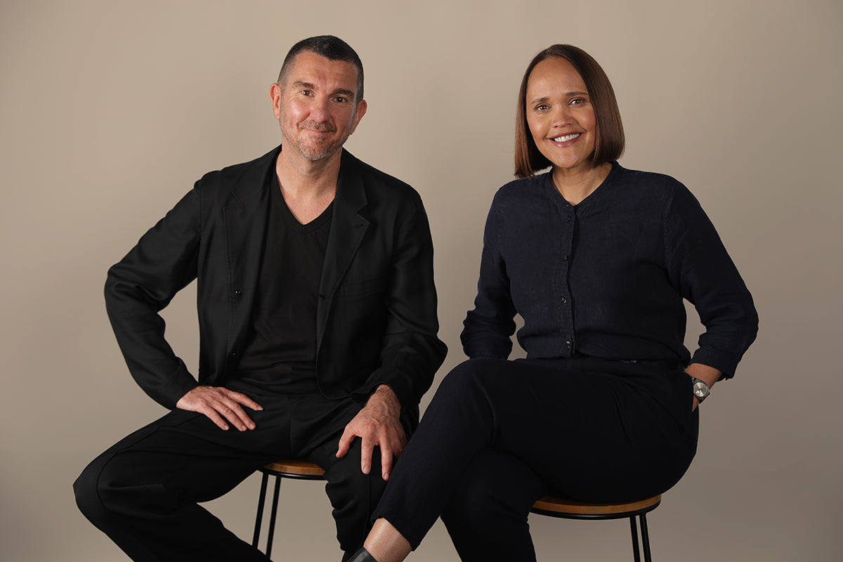 Hivern founders Tamara Tubbs and Christopher Tubbs sit on stools in front of a tan coloured wall